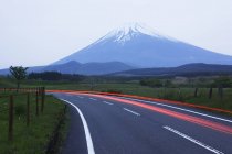 Размытые фары на дороге перед горой, Япония — стоковое фото