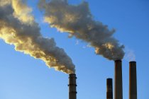 Rauch aus Fabrik stapelt sich vor blauem Himmel — Stockfoto