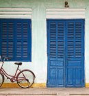 Bike parked on front porch with blue wooden door and window — Stock Photo