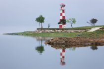 Lighthouse on green beach with reflection in water — Stock Photo
