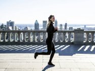 Caucasian woman running in city with skyscrapers in distance, Montreal, Canada — Stock Photo