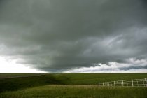Nuvole di tempesta sul paesaggio rurale con recinzione sul campo — Foto stock