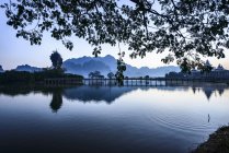 Montañas y puente de reflexión en todavía lago, Hpa-an, Kayin, Myanmar - foto de stock