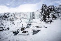 Waterfall pouring over icy cliffs in remote landscape — Stock Photo