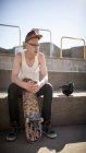 Caucasian man sitting with skateboard at skate park in Canada — Stock Photo