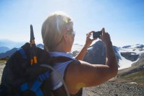 Mujer tomando fotos de montañas remotas en Mt Baker, Washington, EE.UU. - foto de stock