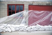 Sandbags and plastic sheet on building wall — Stock Photo
