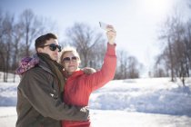 Pareja joven tomando selfie en el parque de invierno - foto de stock