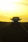 Blurred view of car on road at night with yellow sky — Stock Photo