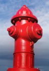 Nahaufnahme eines roten Feuerhydranten vor blauem bewölkten Himmel. — Stockfoto
