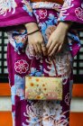 Milieu de la femme en kimono tenant une bourse ornée devant le sanctuaire, Kyoto, Japon — Photo de stock