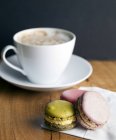 Close-up of macaroon cookies and cup of coffee on table — Stock Photo