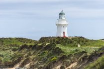 Lighthouse at grassy coastline of Waikawa Point, New Zealand — Stock Photo