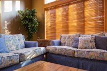 Estores de madeira atrás de sofás na sala de estar — Fotografia de Stock
