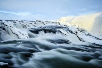 Agua del río que fluye sobre formaciones rocosas heladas - foto de stock