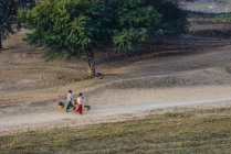 Des populations locales portant des paniers sur un chemin de terre dans un paysage rural, Myanmar — Photo de stock