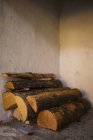 Close-up of firewood stacked in corner indoors — Stock Photo