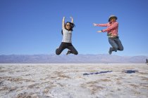 Asian couple jumping near mountain range, Inyo County, California, USA — Stock Photo