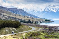 Auto driving near mountains and lake in remote landscape — Stock Photo