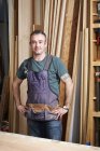 Carpenter standing and smiling in workshop interior — Stock Photo