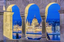 Arches view of Parliament Building illuminated at dusk, Budapest, Hungary — Stock Photo