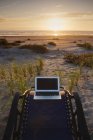 Laptop na cadeira deck com vista para o pôr do sol na praia — Fotografia de Stock
