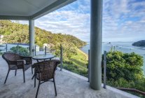 Mesa y sillas en balcón con vistas a la Bahía de las Islas, Paihia, Nueva Zelanda - foto de stock