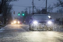 Carros dirigindo na rua urbana nevada em tempo úmido à noite — Fotografia de Stock