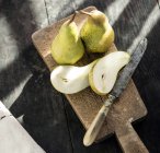 Close-up of fresh sliced pears on wooden board with vintage knife, top view — Stock Photo