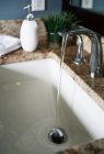 Acqua che scorre dal rubinetto nel lavandino moderno del bagno — Foto stock