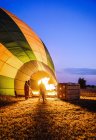 People watching hot air balloon inflating in rural field — Stock Photo