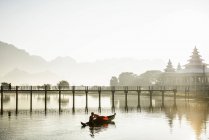 Montagnes et reflet de pont dans le lac tranquille avec bateau avec jeune moine bouddhiste et parasols, Hpa-an, Kayin, Myanmar — Photo de stock