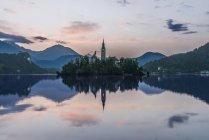 Chiesa ed edifici del villaggio riflessi nel lago tranquillo, Bled, Alta Carniola, Slovenia — Foto stock