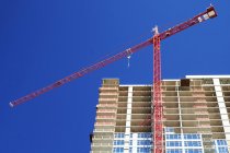 Low angle view of crane building highrise against blue sky — Stock Photo