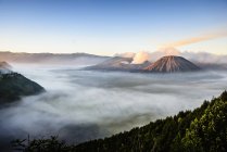 Vista de alto ángulo de las nubes bajo el volcán humeante - foto de stock