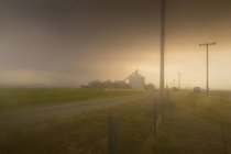 Пыльный шторм над сельской местностью с зерновыми элеваторами на расстоянии — стоковое фото