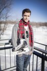 Giovane uomo caucasico che trasporta pattini da ghiaccio in inverno — Foto stock