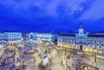 Ornate buildings illuminated at night at square with crowd of people, Madrid, Madrid, Spain — Stock Photo