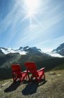 Cadeiras de gramado vermelho perto paisagem montanhosa cênica — Fotografia de Stock