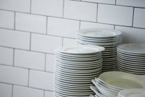 Primo piano di piatti impilati nella cucina del ristorante con piastrelle bianche — Foto stock