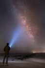 Rear view of man shining flashlight on starry sky, Cape May, New Jersey, USA — Stock Photo