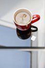 Tea bag steeping in mug on glass table. — Stock Photo