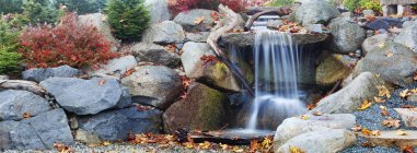 Autumn leaves around waterfall feature — Stock Photo