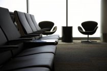 Cadeiras na área de espera do aeroporto por janela — Fotografia de Stock