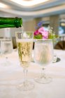 Pouring champagne into drinking glasses on table, close-up — Stock Photo