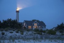 Faro che irradia vicino casa sulla spiaggia in New Jersey, Stati Uniti d'America — Foto stock