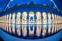 Arcos de azulejos adornados de la Gran Mezquita iluminando por la noche, Abu Dhabi, Emiratos Árabes Unidos - foto de stock