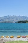Kayaks atracados a lo largo de la playa, Lago Wanaka, Otago, Nueva Zelanda - foto de stock