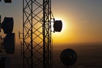 Silhouette de la torre de comunicaciones contra el cielo del sol - foto de stock