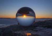 Close-up of sunset horizon inverted in glass sphere on beach — Stock Photo